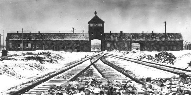 Eisenbahnschienen, die in ein Gebäude in Ausschwitz führen, schwarz-weiß