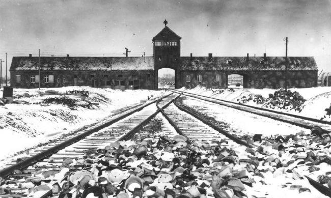 Eisenbahnschienen, die in ein Gebäude in Ausschwitz führen, schwarz-weiß