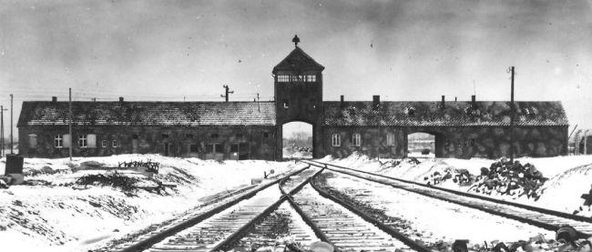 Eisenbahnschienen, die in ein Gebäude in Ausschwitz führen, schwarz-weiß