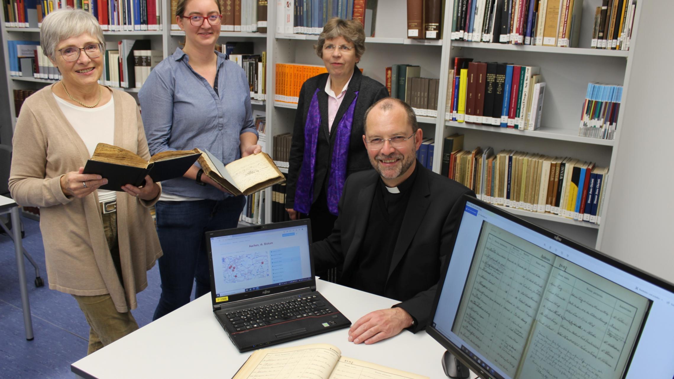 Mit 80.000 digitalisierten Seiten aus Kirchenbüchern startet das Bistum Aachen auf der Online-Plattform 'Matricula': Die Archivarinnen Marita Hermanns-Kuck (v.l.) und Charlotte Treutler drückten gemeinsam mit Dr. Beate Fleck, Leiterin des Diözesanarchivs, und Generalvikar Dr. Andreas Frick symbolisch den Startknopf.