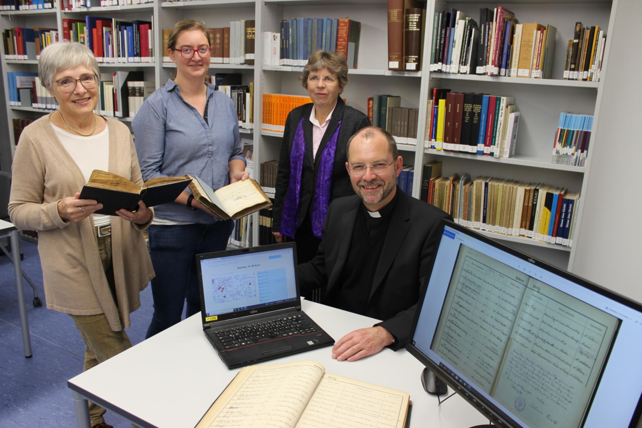 Mit 80.000 digitalisierten Seiten aus Kirchenbüchern startet das Bistum Aachen auf der Online-Plattform 'Matricula': Die Archivarinnen Marita Hermanns-Kuck (v.l.) und Charlotte Treutler drückten gemeinsam mit Dr. Beate Fleck, Leiterin des Diözesanarchivs, und Generalvikar Dr. Andreas Frick symbolisch den Startknopf.
