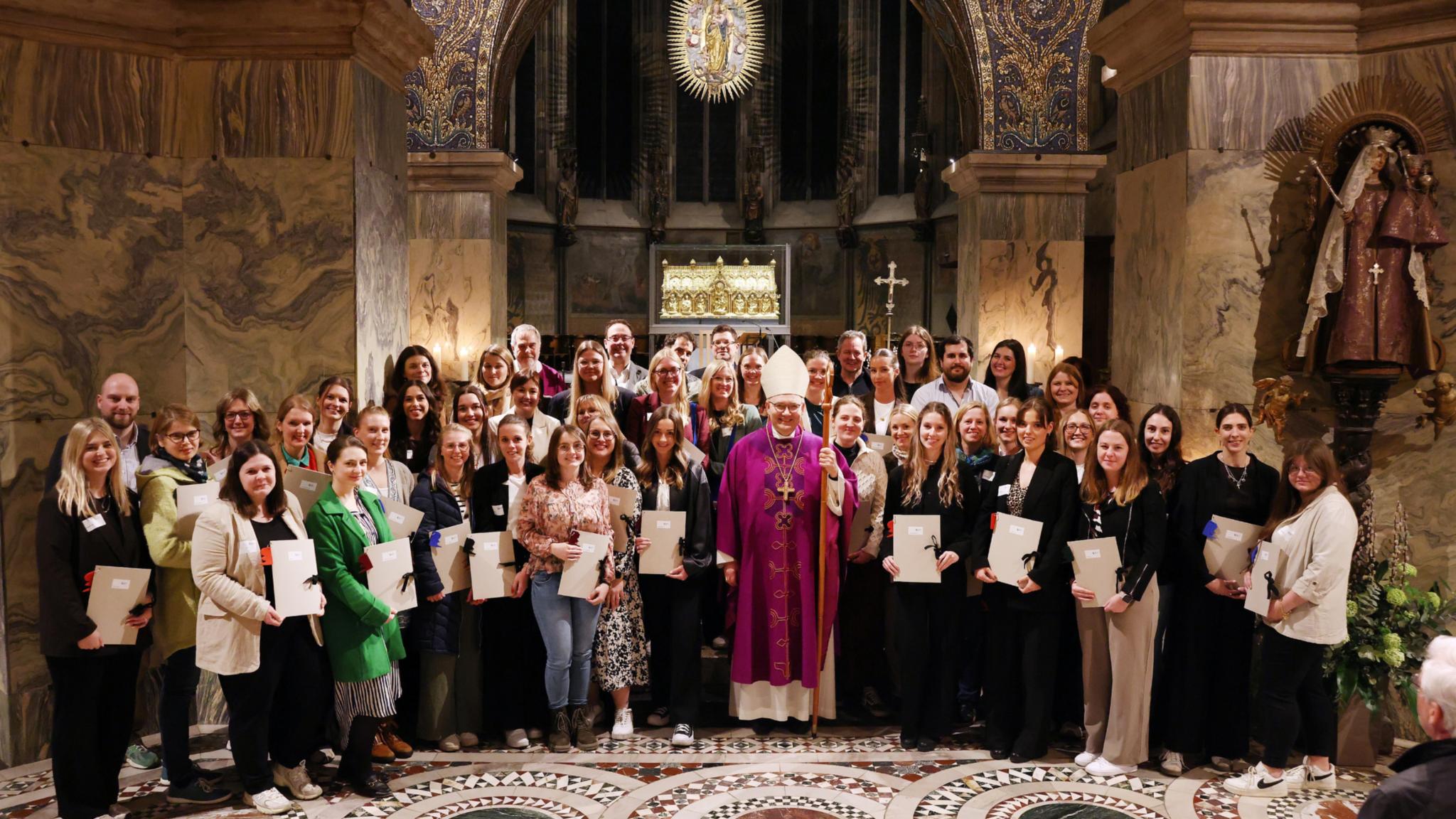 Menschen mit Urkunden in der Hand  stehen um Bischof Dieser im Aachener Dom vor dem Altar