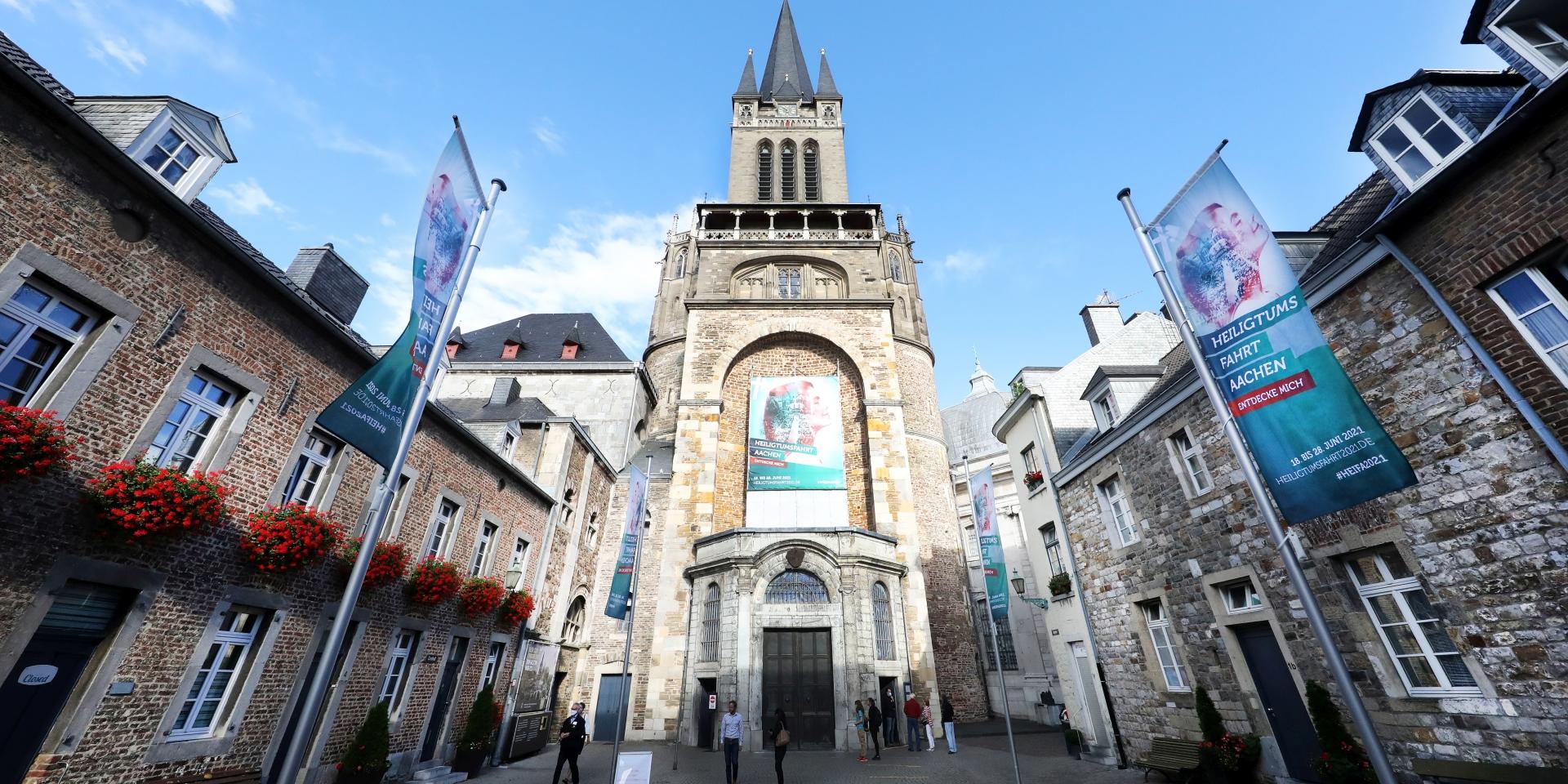 Rund um den Aachener Dom erstrahlt nicht nur auf zahlreichen Fahnen das Grün der Heiligtumsfahrt: Über dem Hauptportal des Doms weist ein Großtransparent auf die Wallfahrt hin, die vom 18. bis 28. Juni 2021 stattfindet.