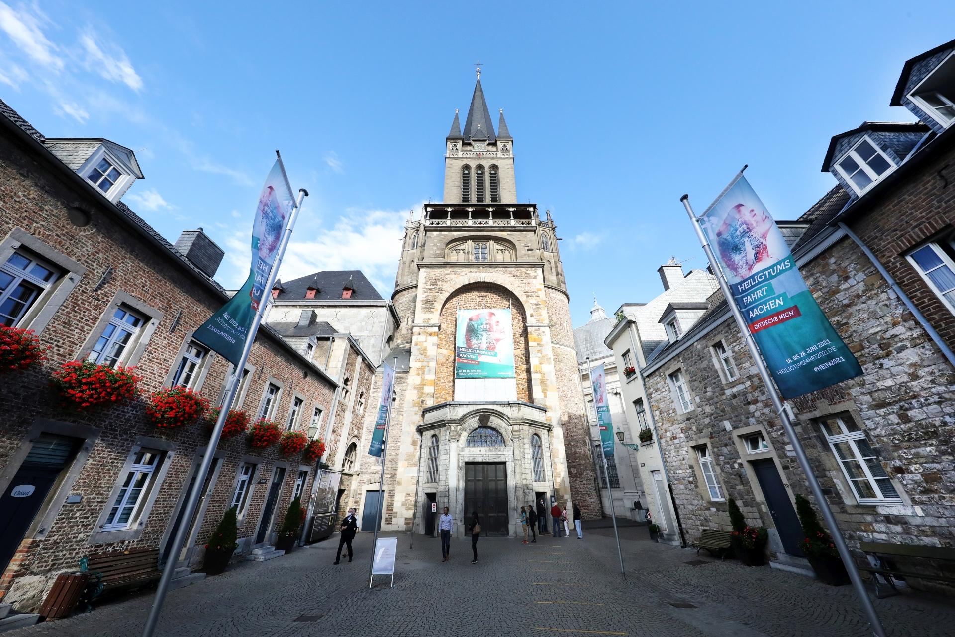 Rund um den Aachener Dom erstrahlt nicht nur auf zahlreichen Fahnen das Grün der Heiligtumsfahrt: Über dem Hauptportal des Doms weist ein Großtransparent auf die Wallfahrt hin, die vom 18. bis 28. Juni 2021 stattfindet.