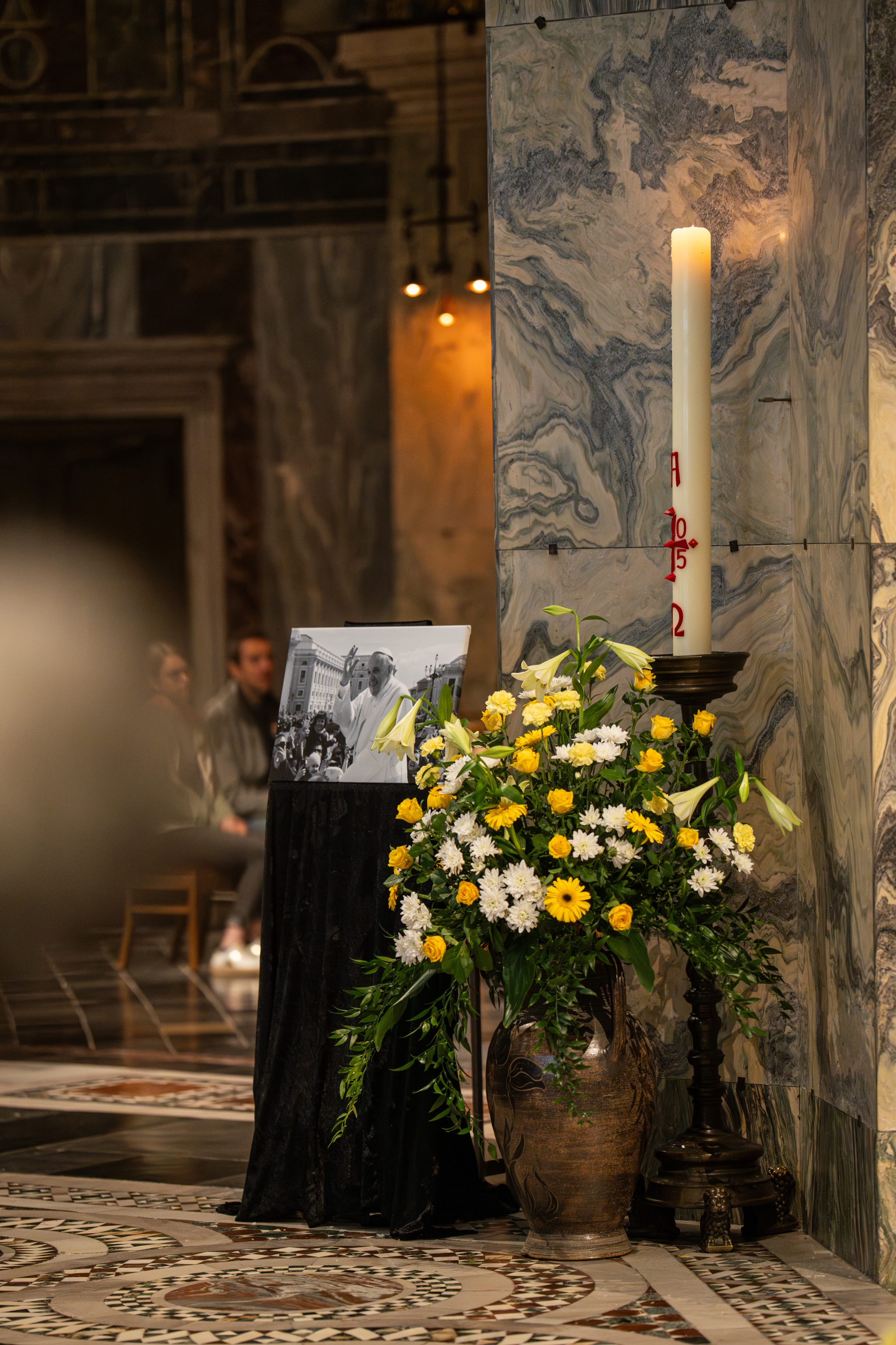 Bild von Papst Franziskus neben einer Osterkerze, vor einer Säule im Aachener Dom