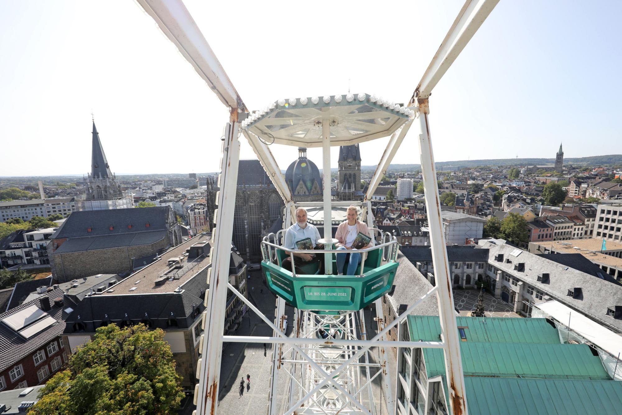 Mit der grünen Gondel zur Heiligtumfahrt Aachen geht es hoch hinaus: Am höchsten Punkt erreicht das Riesenrad 45 Meter Höhe und bietet einen großartigen Blick auf den Aachener Dom. Das ließen sich auch Dompropst und Wallfahrtsleiter Rolf-Peter Cremer sowie Projektmitarbeiterin Nadine Braun nicht entgehen.