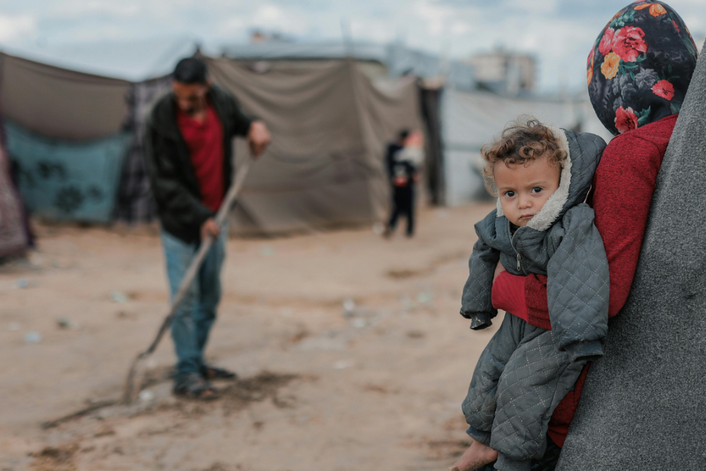 Kriegslager, Frau hat Kind auf dem Arm, Zelte aufgebaut