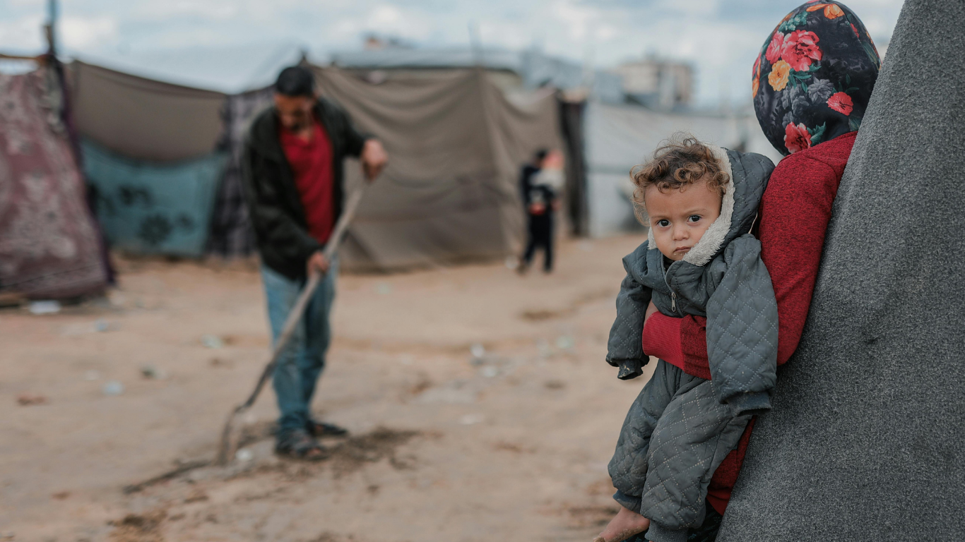 Kriegslager, Frau hat Kind auf dem Arm, Zelte aufgebaut