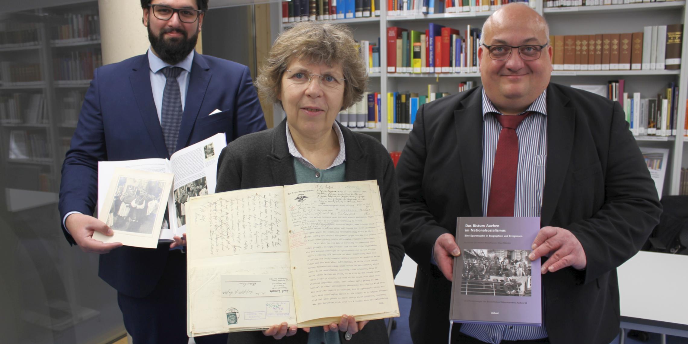 „Die Offenheit des Bistums und die gute Zusammenarbeit haben die Grundlagenforschung für dieses Projekt wirklich fruchtbar gemacht“, betonen die beiden  Historiker beim Landschaftsverband Rheinland (LVR), Dr. Helmut Rönz (r.) und Keywan Klaus Münster (l.). Sie präsentieren das Buch gemeinsam mit Dr. Beate Sophie Fleck (M.), Direktorin des Diözesanarchivs Aachen.