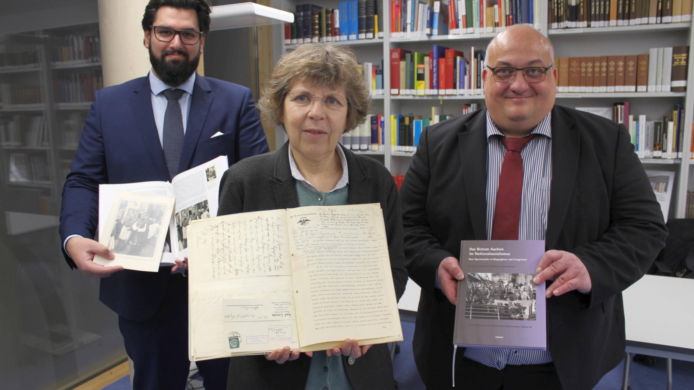 „Die Offenheit des Bistums und die gute Zusammenarbeit haben die Grundlagenforschung für dieses Projekt wirklich fruchtbar gemacht“, betonen die beiden Historiker beim Landschaftsverband Rheinland (LVR), Dr. Helmut Rönz (r.) und Keywan Klaus Münster (l.). Sie präsentieren das Buch gemeinsam mit Dr. Beate Sophie Fleck (M.), Direktorin des Diözesanarchivs Aachen.