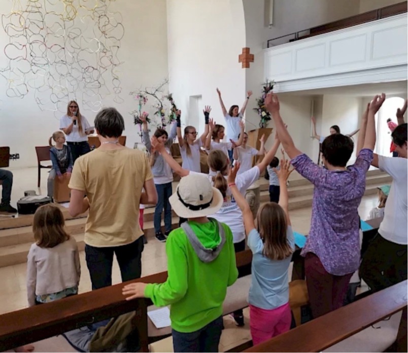 Familiengottesdienst Familien singen mit einer Musikgruppe in einem Gottesdienstraum