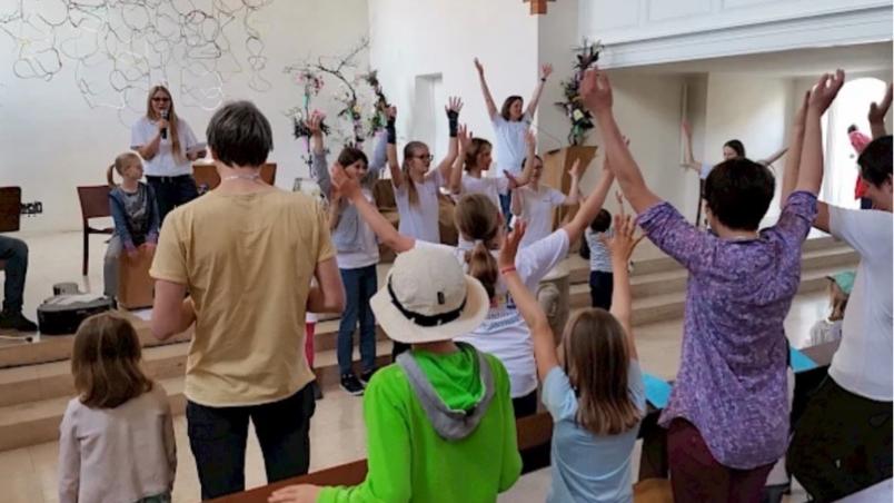 Familien singen mit einer Musikgruppe in einem Gottesdienstraum