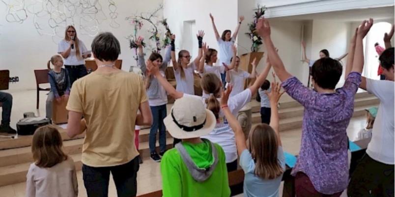 Familiengottesdienst Familien singen mit einer Musikgruppe in einem Gottesdienstraum