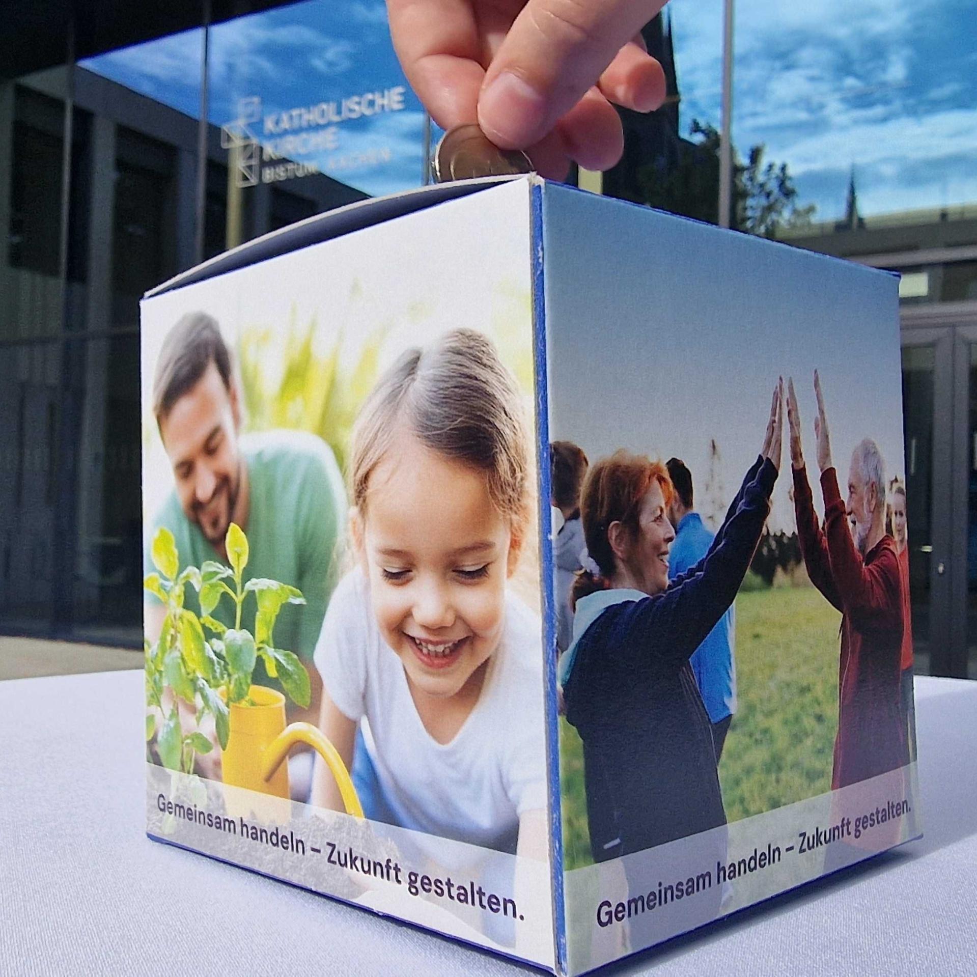 Eine Person wirft Geld in eine Spendenbox