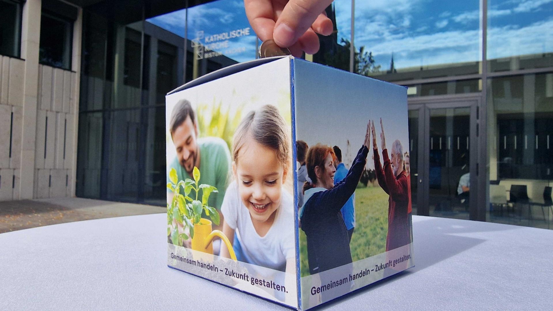 Eine Person wirft Geld in eine Spendenbox