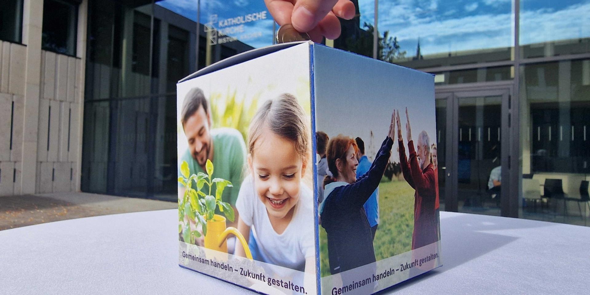 Eine Person wirft Geld in eine Spendenbox