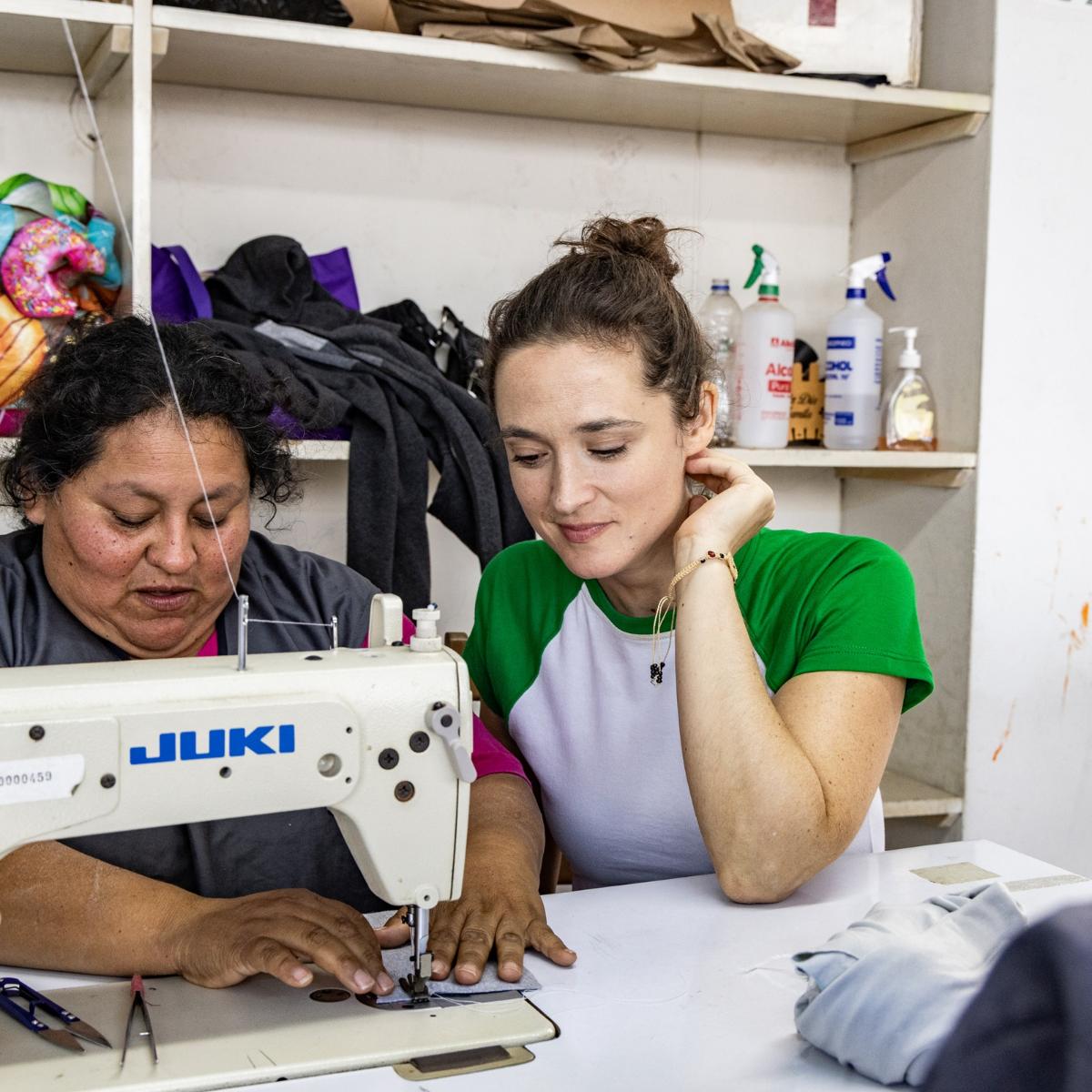 Die Bochumer Schauspielerin Friederike Becht schaut Susana Raquel Guiller Alegría von der Asociación Papico beim Nähen über die Schulter. Nachdem eine Ölpest den Fischern die Lebensgrundlage entzogen hatte, hat Susana mit anderen Frauen die Initiative ergriffen. Die Teilnehmerinnen ihrer Nähkurse erhalten Zertifikate, sodass sie auch normierte Produkte wie Schulkleidung anbieten und so mehr Geld verdienen können.