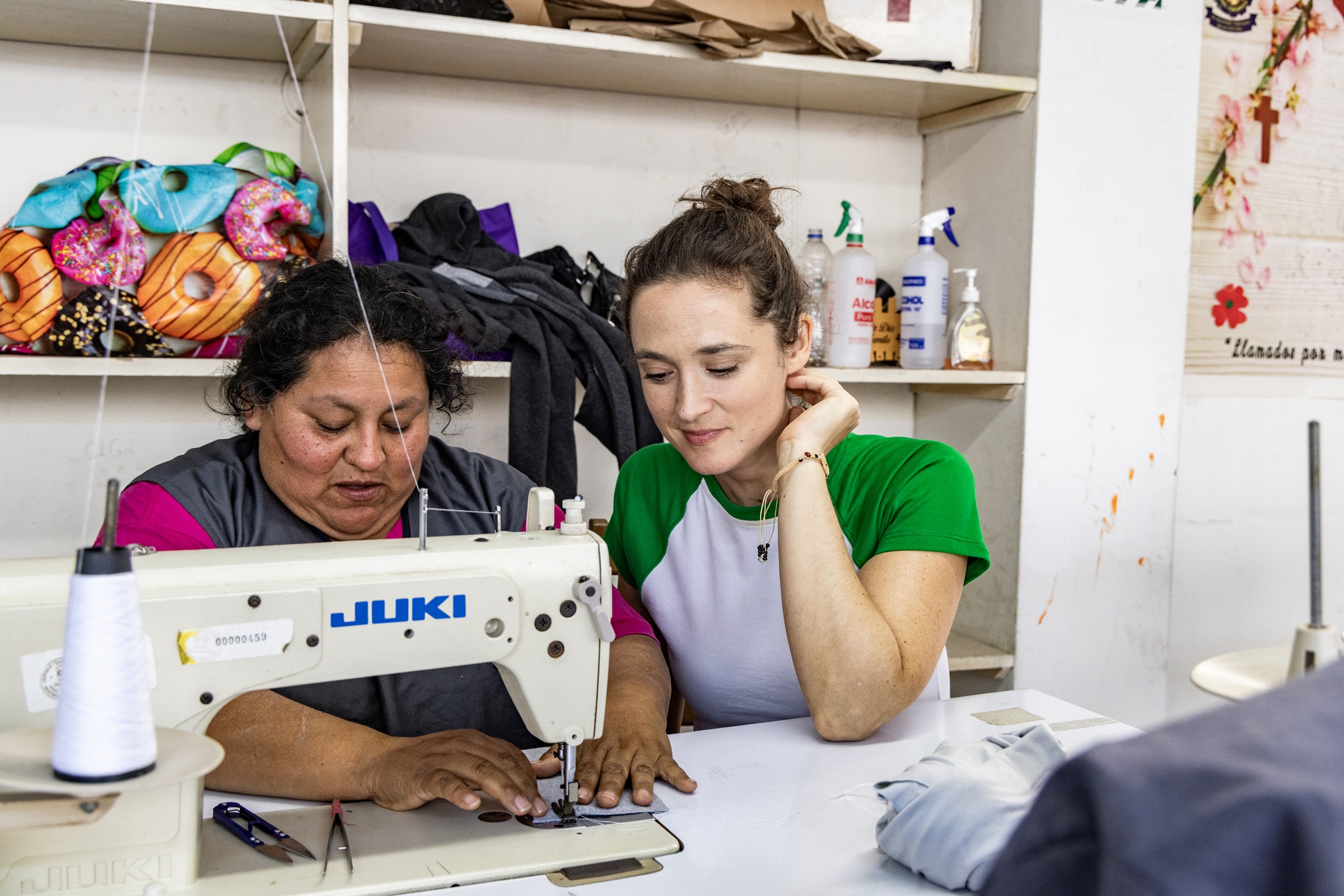 Die Bochumer Schauspielerin Friederike Becht schaut Susana Raquel Guiller Alegría von der Asociación Papico beim Nähen über die Schulter. Nachdem eine Ölpest den Fischern die Lebensgrundlage entzogen hatte, hat Susana mit anderen Frauen die Initiative ergriffen. Die Teilnehmerinnen ihrer Nähkurse erhalten Zertifikate, sodass sie auch normierte Produkte wie Schulkleidung anbieten und so mehr Geld verdienen können.