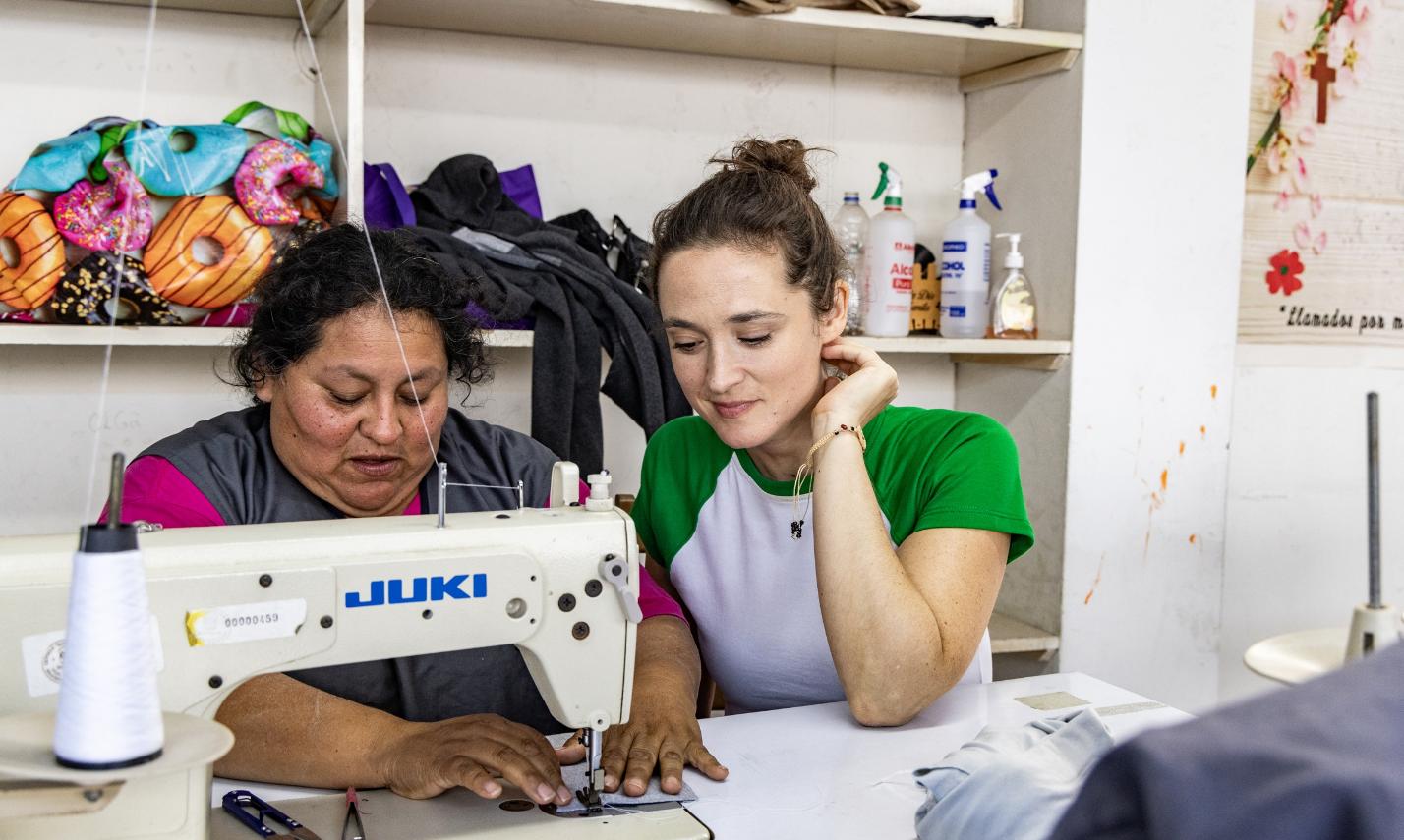 Die Bochumer Schauspielerin Friederike Becht schaut Susana Raquel Guiller Alegría von der Asociación Papico beim Nähen über die Schulter. Nachdem eine Ölpest den Fischern die Lebensgrundlage entzogen hatte, hat Susana mit anderen Frauen die Initiative ergriffen. Die Teilnehmerinnen ihrer Nähkurse erhalten Zertifikate, sodass sie auch normierte Produkte wie Schulkleidung anbieten und so mehr Geld verdienen können.