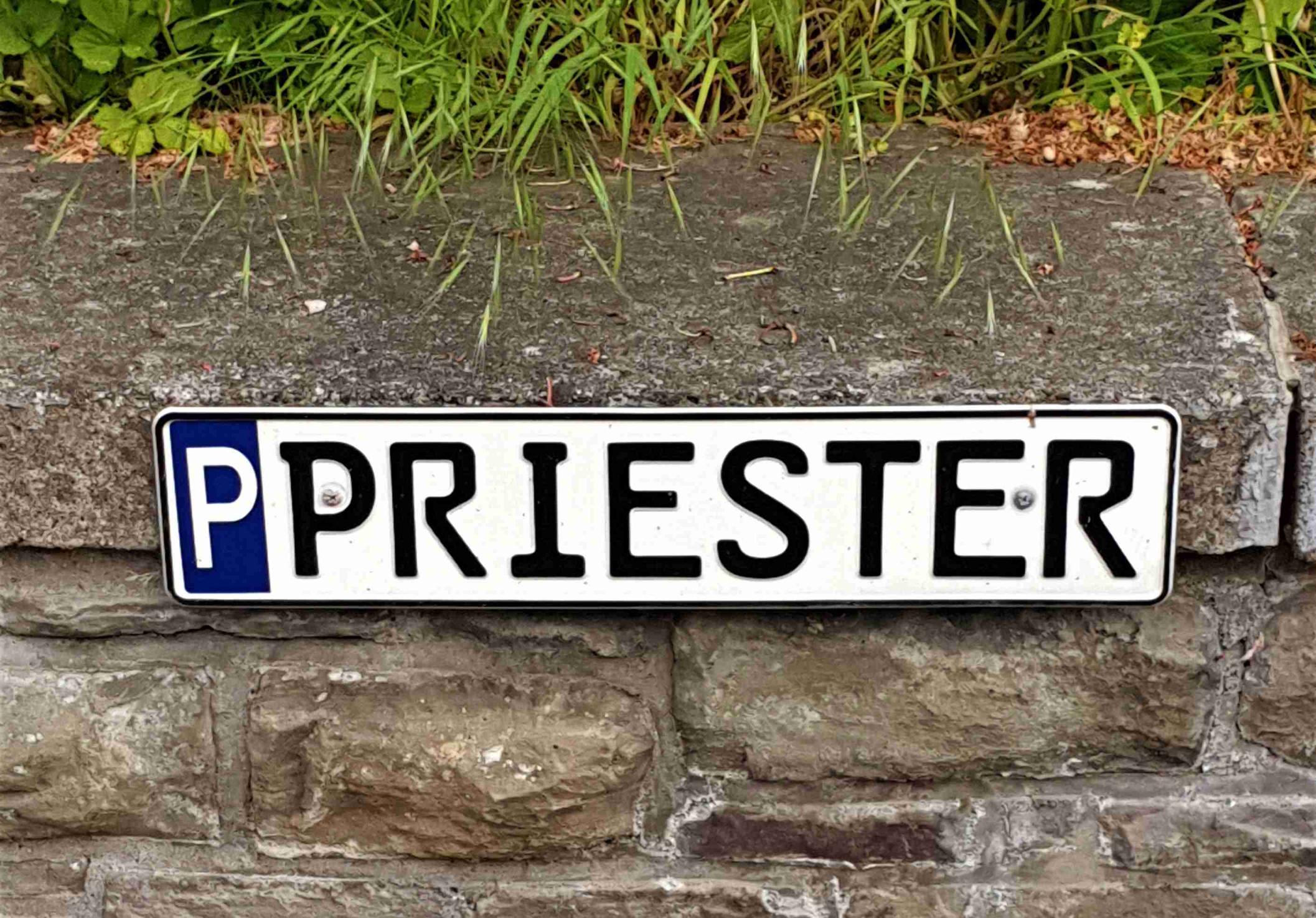 Ein Schild weist einen Parkplatz für den Priester aus.
