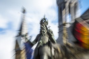 Verwischtes Bild der Statue Kaiser Karls vor dem Aachener Rathaus mit Europaflagge und Deutschlandflagge)