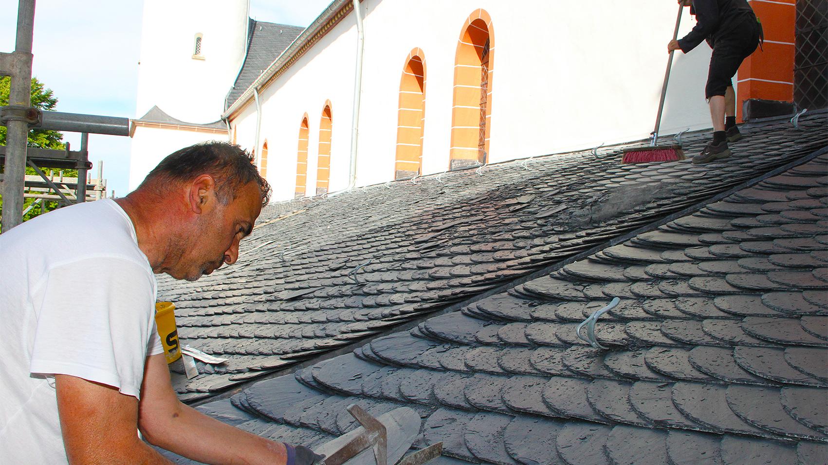 Gemäß „Altdeutscher Deckung“ ein Dach zu beschiefern, das kann nicht jeder Dachdecker. Geselle Ergin Birihci (vorne) weiß, wie es geht. Gesellenkollege Heinz Beyer fegt das Dach.