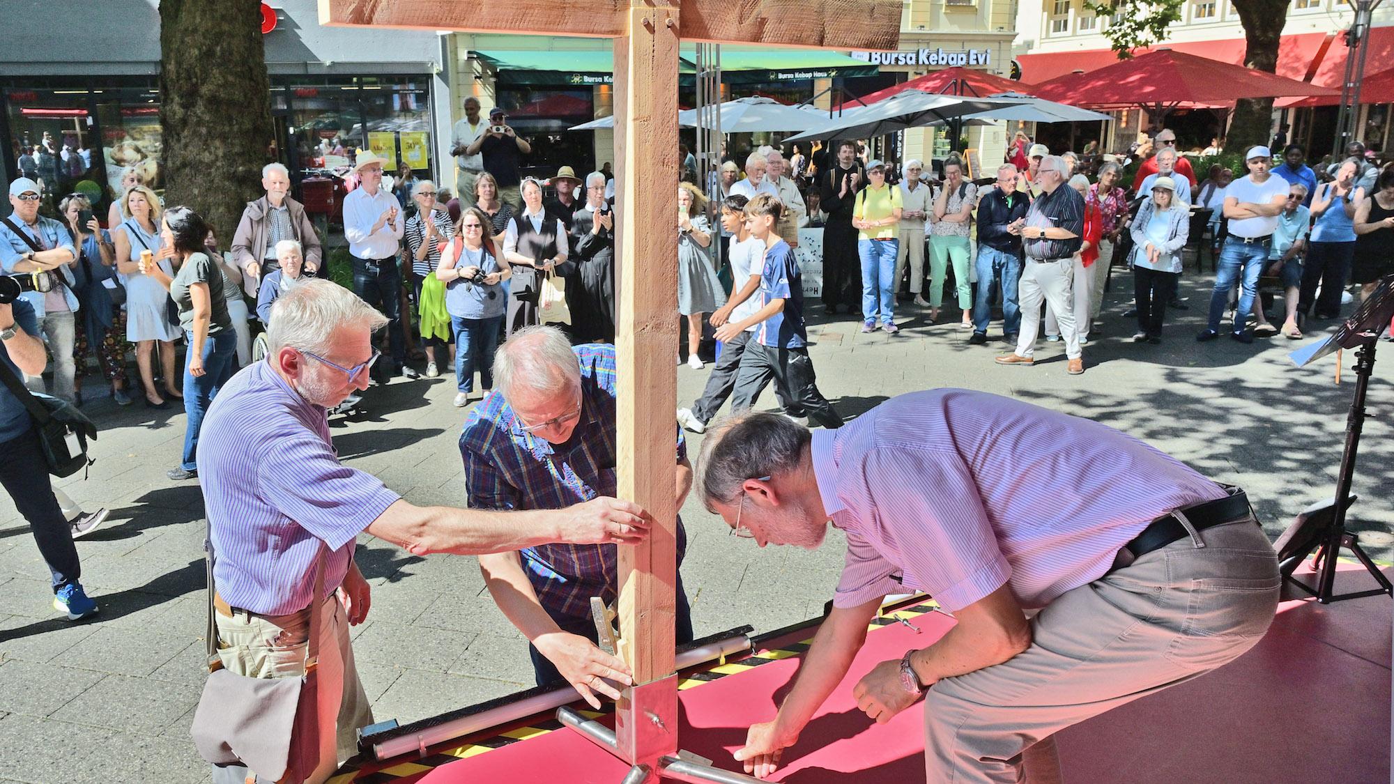 Auf dem Neumarkt werden die vier Kreuzteile, die die Teilnehmer der vier Wallprozessionen getragen haben, zusammengesetzt.