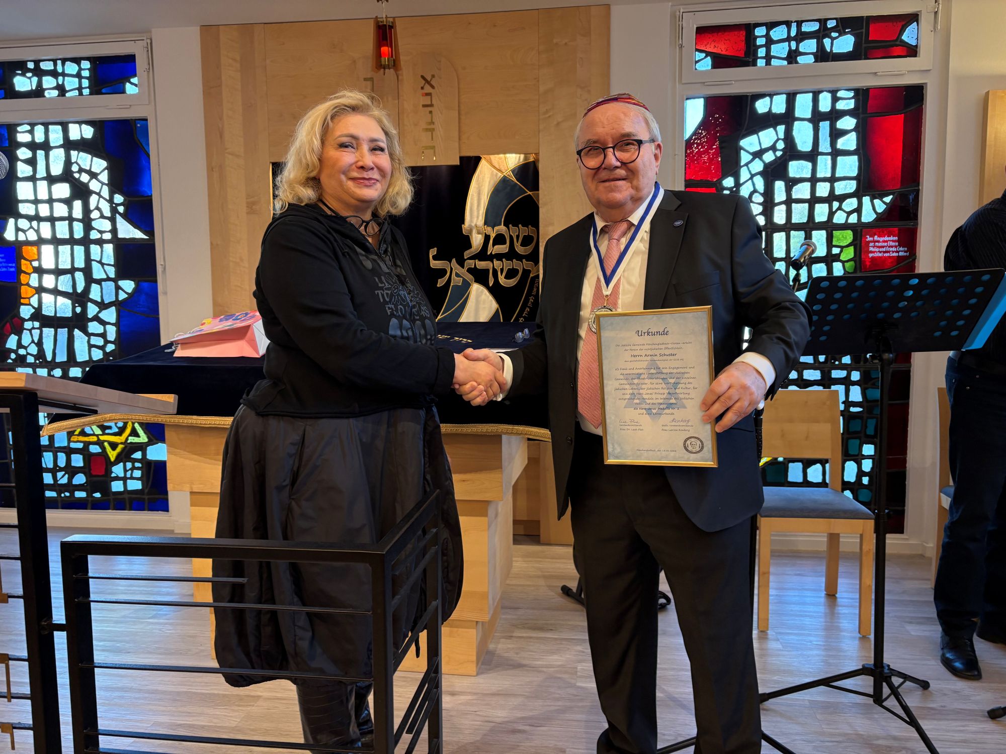 Leah Floh, Vorsitzende der jüdischen Gemeinde, zeichnet Armin Schuster, Vorsitzender der GCJZ, mit der Hans-Jonas-Medaille aus.