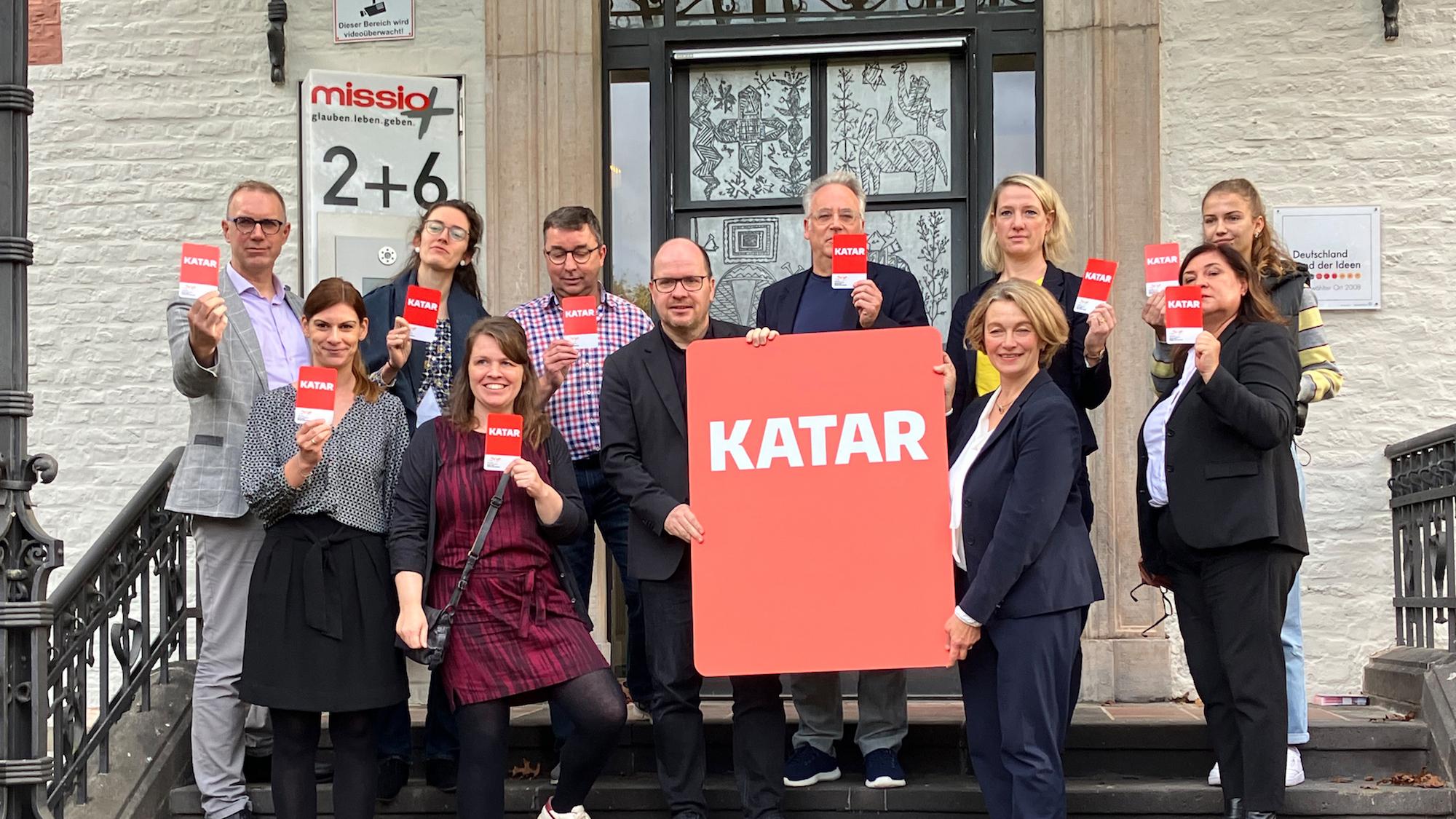 Das Team der Schutzengel-Kampagne, zu der auch die Katar-Aktion gehört, hält vor der Zentrale des Hilfswerks gemeinsam mit Missio-Präsident Pfarrer Dirk Bingener (Mitte) rote Karten in die Höhe.