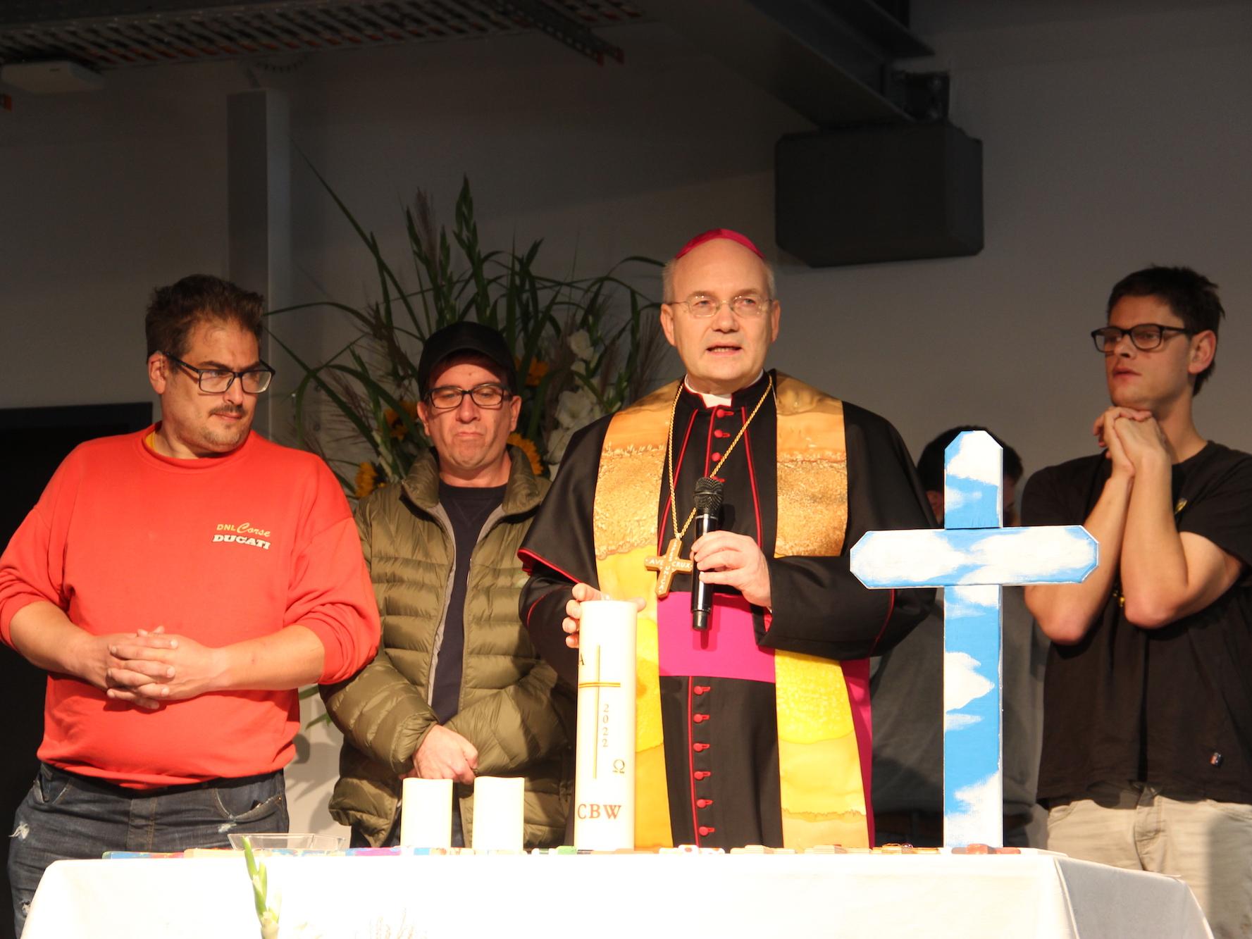 Bischof Helmut Dieser hat sich Verstärkung an den Altar geholt, um gemeinsam mit  einigen der Menschen mit Behinderung eine Kerze für ihre neue Werkstatt zu entzünden.