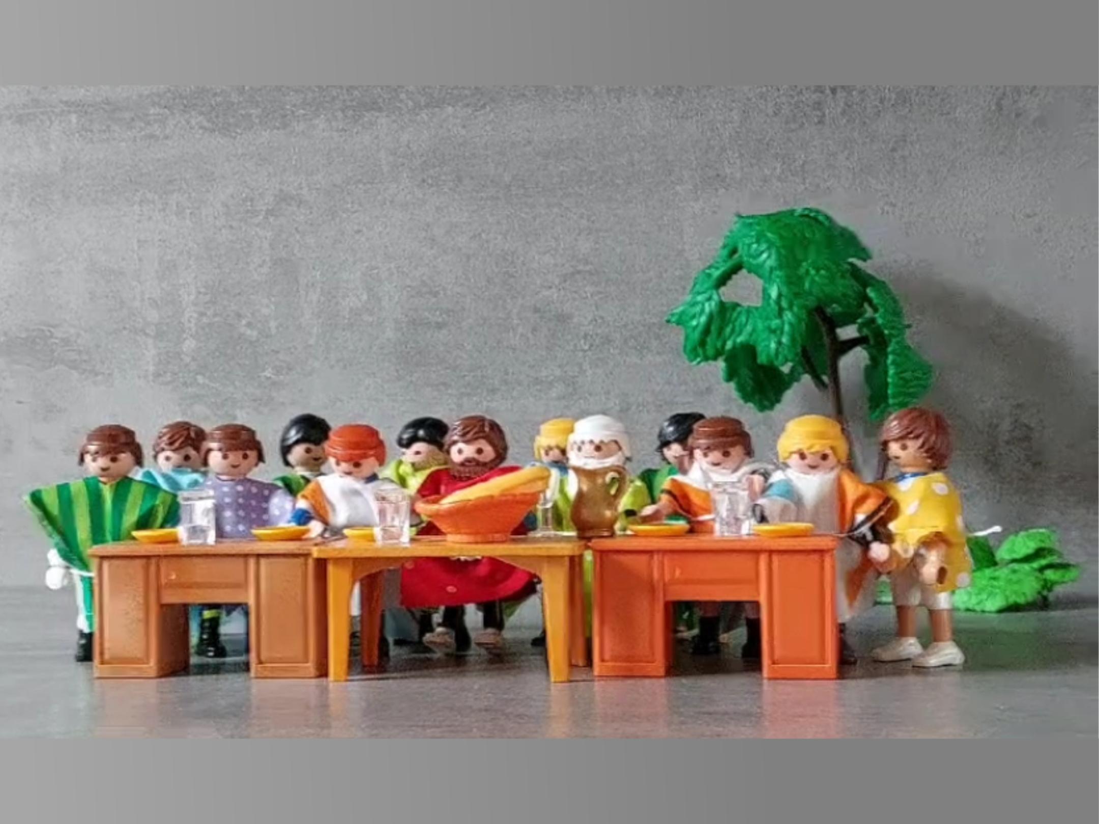 13 Playmobilmännchen sitzen an einem Tisch.