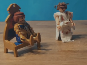 Ein Playmobilmännchen steht vor einem weiteren Playmobilmännchen  auf Thron.