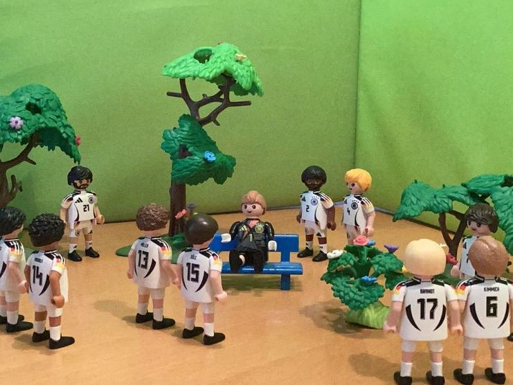 Playmobilmännchen als Fussballmannschaft gekleidet stehen immer zu zweit zusammen.