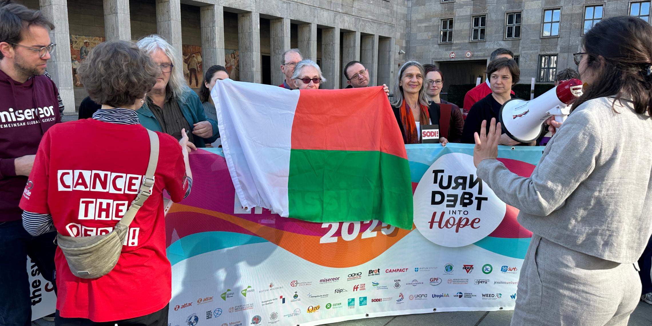 Stellvertretend für die Länder des globalen Südens haben wir die Fahne Madagaskars ins Bild gesetzt.